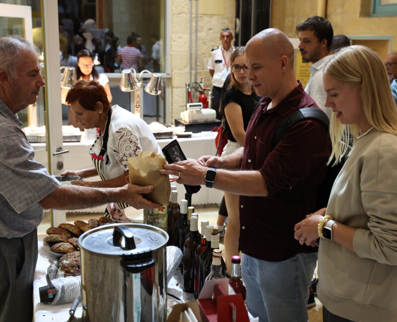 A photo showing people enjoying the Valletta Local Food Festival at the Upper Barrakka Gardens, surrounded by stalls filled with local produce, artisanal food, and traditional Maltese flavours.