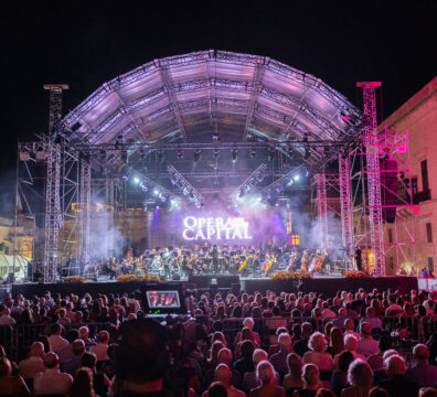 An image showing the stage with the text Opera in the Capital and audience in St George's Square, Valletta